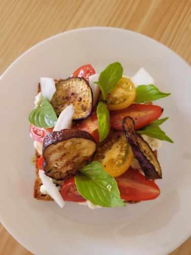 L'image représente une tartine de tomate, basilic & aubergines